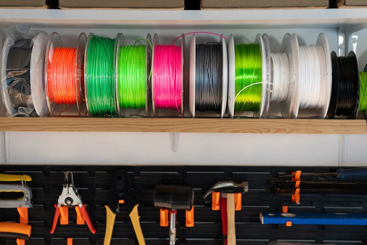 Colorful 3D printing filament spools on a workshop shelf